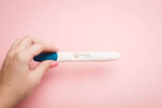 Pregnancy test in hand on a pink background . Positive test. Pregnancy copy space. Motherhood