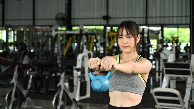 Young woman fitness training with kettlebell in sport gym.