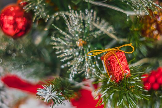 Christmas tree artificial decorative plastic green shiny sequins sprinkles, LED garland light, red gift present toy. Winter holiday leisure. Bright effect tone