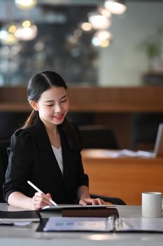 Portrait charming businesswoman using digital tablet at her office desk.