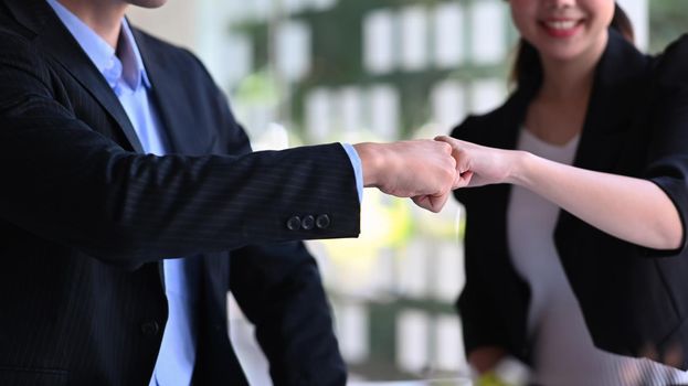 Cropped shot business partners giving fist bump after complete a deal or celebrating successful.