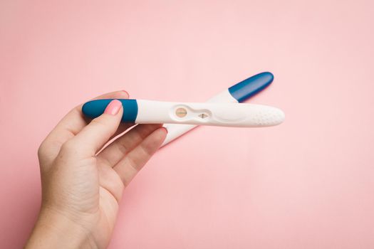 Pregnancy test in hand on a pink background . Positive test. Pregnancy copy space. Motherhood