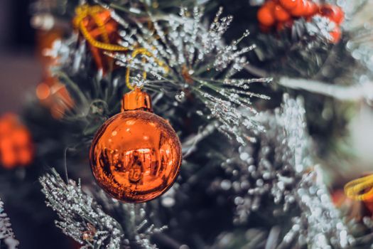 Christmas tree artificial decorative plastic green shiny sequins sprinkles, LED garland light, red ball toy reflection. Winter holiday leisure. Bright white gray effect tone.