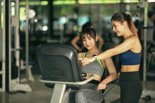 Two beautiful fitness woman working out in gym together.