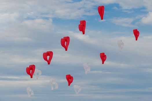 Red and white kites hearts are flying in the wind at the festival of kites