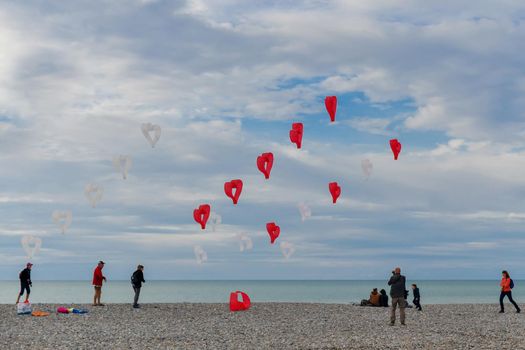 DIEPPE, FRANCE - SEPTEMBER 08, 2018: Red and white kites hearts are flying in the wind at the festival of kites