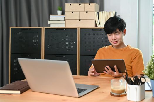 Happy asian man using digital tablet at home.