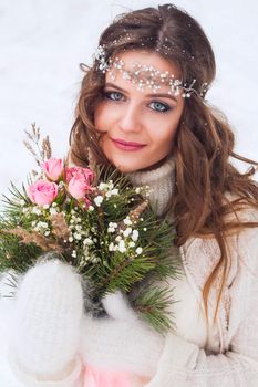 Beautiful bride in a white dress with a bouquet in a snow-covered winter forest. Portrait of the bride in nature.Beautiful bride in a white dress with a bouquet in a snow-covered winter forest. Portrait of the bride in nature.