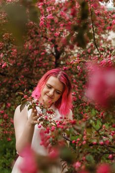 Young girl with pink hair in an Apple orchard. Beautiful young girl in a blooming garden of pink Apple trees.