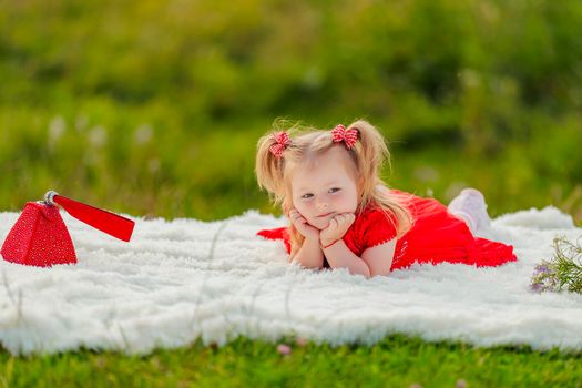 little girl in a red dress lies on a white blanket