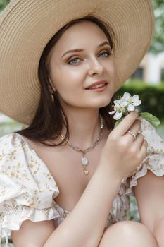 An attractive long-haired woman walks in the spring in the park of blooming apple trees. Spring portrait of a woman