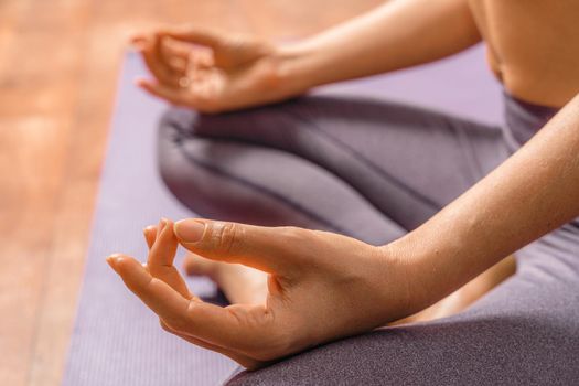 Young woman meditating in the lotus pose at home. Practicing yoga indoors. Harmony, yoga practice, balance, meditation, relaxation at home, healthy lifestyle concept