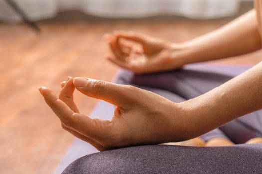 Young woman meditating in the lotus pose at home. Practicing yoga indoors. Harmony, yoga practice, balance, meditation, relaxation at home, healthy lifestyle concept