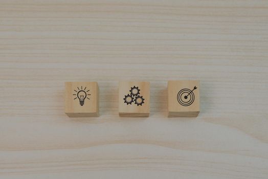 Strategy goals and investment plan business marketing icon symbol gear and light bulb with wood block cube on table.