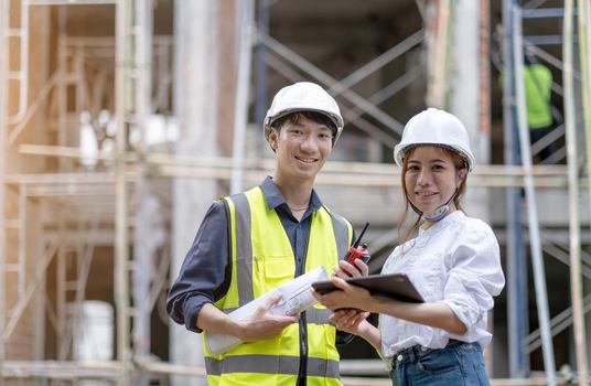 Portrait of a team of successful contractors/investors/architectural engineers wearing helmets and safety vests standing on a commercial building construction site