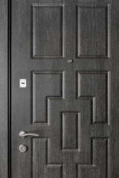Wooden dark door entrance, with iron handle, key lock hole and peephole.