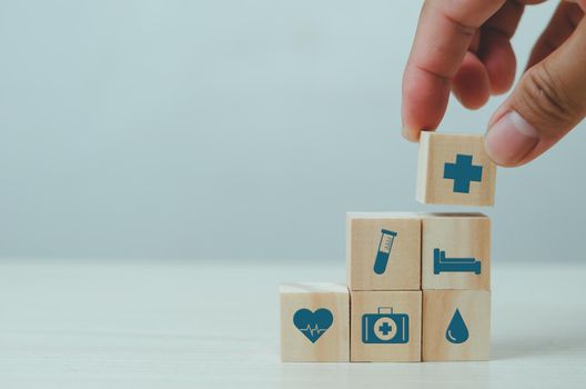 Hand put wooden cubes with insurance health care medical symbol on table copy space.Business concepts.