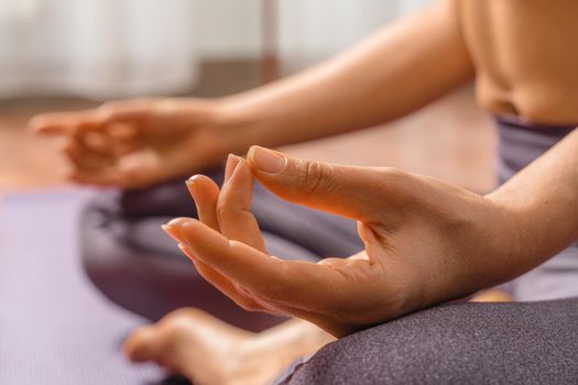 Young woman meditating in the lotus pose at home. Practicing yoga indoors. Harmony, yoga practice, balance, meditation, relaxation at home, healthy lifestyle concept