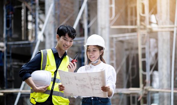 asian architect and mature supervisor meeting at construction site. worker and engineer discussing on plan. Two construction workers working together while visiting a new building..