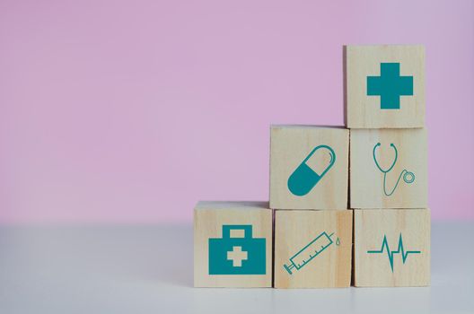 Wooden cubes block with insurance health car medical symbol on the pink background and copy space.