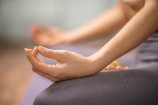 Young woman meditating in the lotus pose at home. Practicing yoga indoors. Harmony, yoga practice, balance, meditation, relaxation at home, healthy lifestyle concept