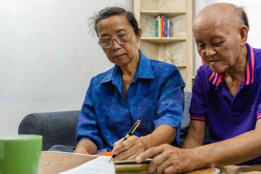 Asian elderly holding pen contract payment credit card insurance health care paperwork or document report shopping finance concept.