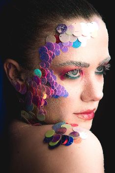 Creative sandy face makeup of a girl with colorful sequins