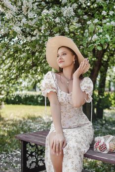 An attractive long-haired woman walks in the spring in the park of blooming apple trees. Spring portrait of a woman