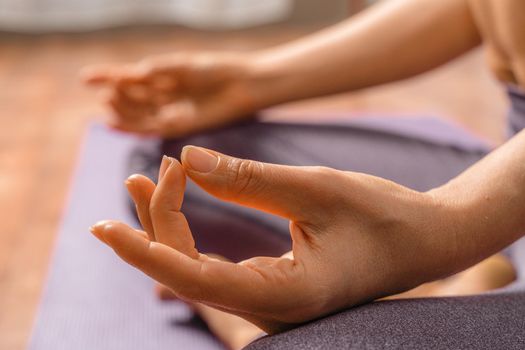 Young woman meditating in the lotus pose at home. Practicing yoga indoors. Harmony, yoga practice, balance, meditation, relaxation at home, healthy lifestyle concept