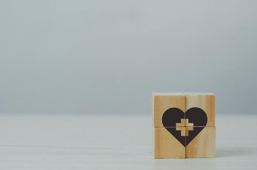 Wooden cube with health insurance icon on table background.