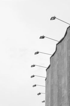 Concrete old building architecture structure cement facade apartment stone with elements of illumination bulbs on the roof against a background of gray sky.