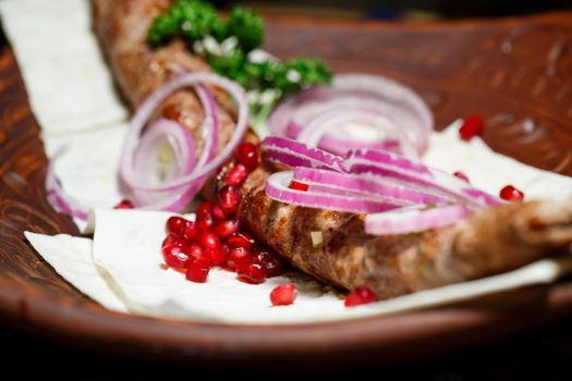 A dish cooked on the kebab grill. Georgian dishes. Garnished with onions and pomegranate seeds