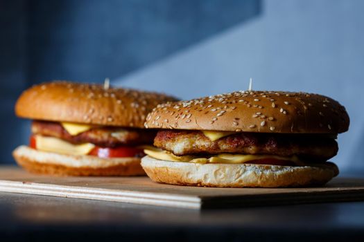 Large juicy burger with cutlet cheese and tomatoes. Fast food