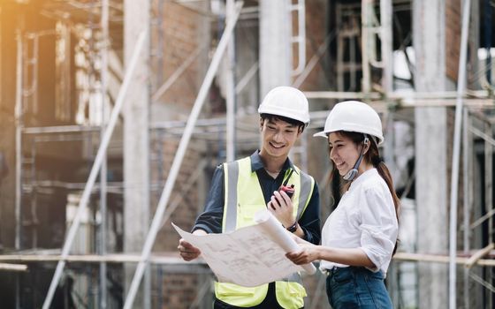 asian architect and mature supervisor meeting at construction site. worker and engineer discussing on plan. Two construction workers working together while visiting a new building..