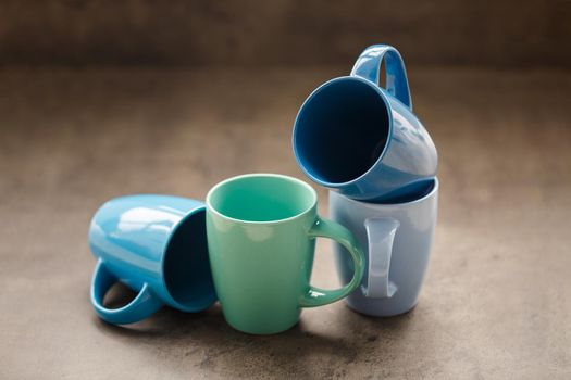 four tea mugs of different colors on a gray background
