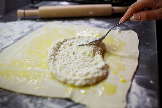 Baking domestic rolls with cheese. Putting cheese on dough for rolls