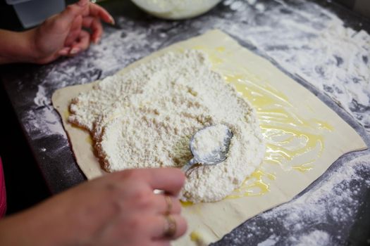 Baking domestic rolls with cheese. Putting cheese on dough for rolls