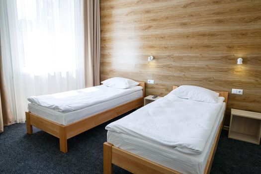 Large bright room in a hostel with three beds. White bedding