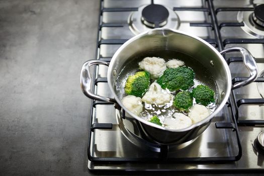 Broccoli and cauliflower boiled in a gray saucepan on a gas stove