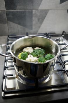 Broccoli and cauliflower boiled in a gray saucepan on a gas stove