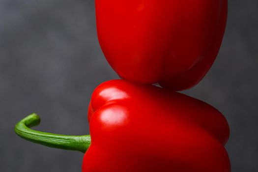 Two red peppers on a grey table