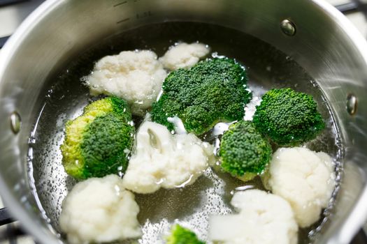Broccoli and cauliflower boiled in a gray saucepan on a gas stove