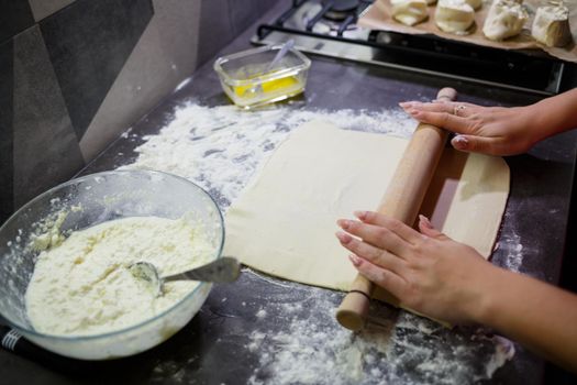 Baking domestic rolls with cheese. Putting cheese on dough for rolls