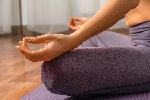 Young woman meditating in the lotus pose at home. Practicing yoga indoors. Harmony, yoga practice, balance, meditation, relaxation at home, healthy lifestyle concept