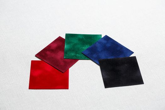 square pieces of multi-colored fabric laid out on a gray background