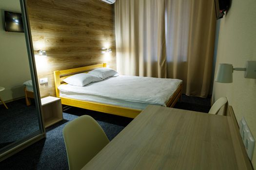 Large bright room in the hotel with a bed, TV, wardrobe. White bedding. Hotel room
