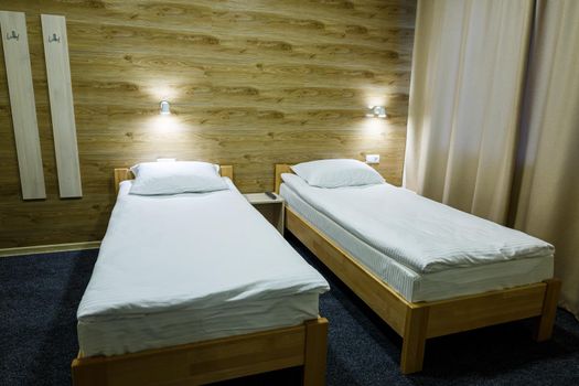 Large bright room in a hostel with three beds. White bedding