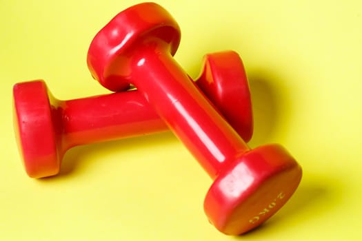 red sports dumbbells on a yellow background