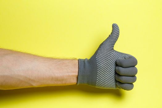 hand of a man, craftsman, gardener in a gray glove on a yellow background