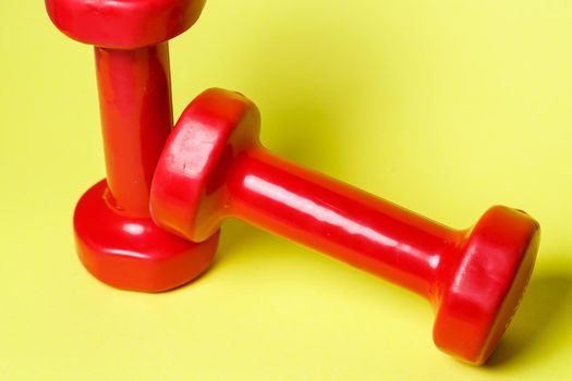 red sports dumbbells on a yellow background
